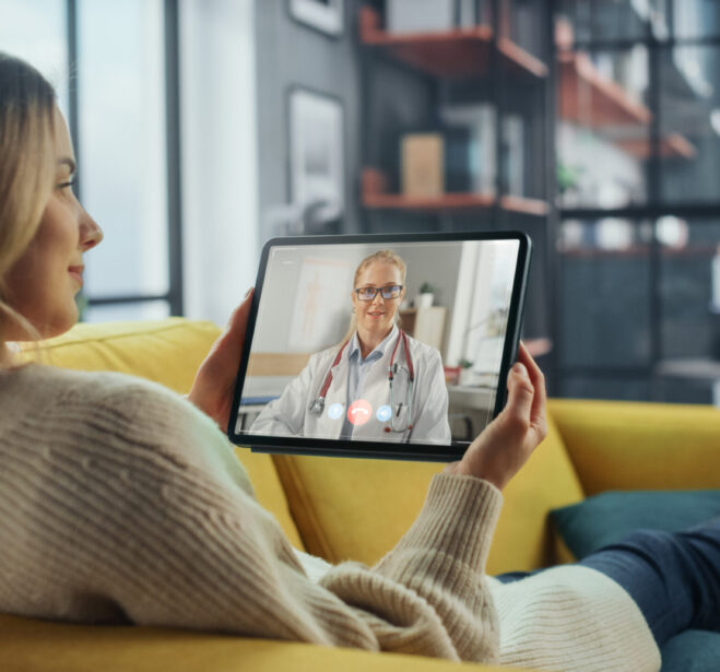 Close Up of a Female Chatting in a Video Call with Her Female Family Doctor on Digital Tablet from Living Room. Ill-Feeling Woman Making a Call from Home with Physician Over the Internet.